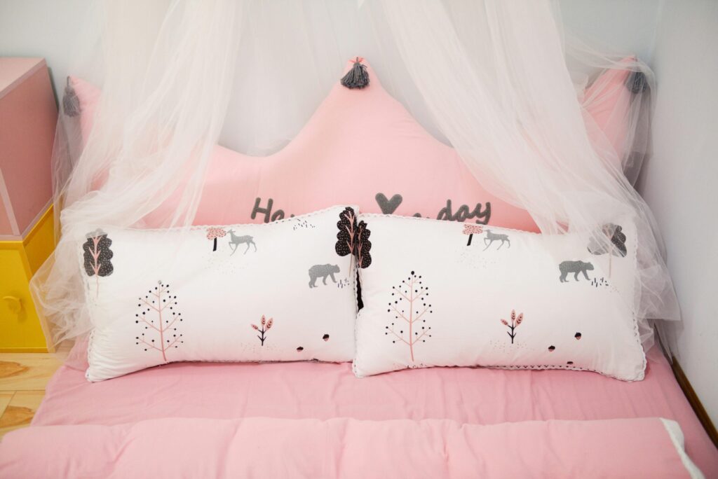 A charming children’s bed featuring pink decor, pillows with animal designs, and a canopy.